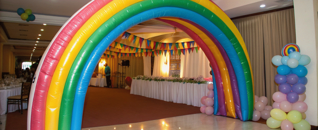 A rainbow balloon arch in a party hall.