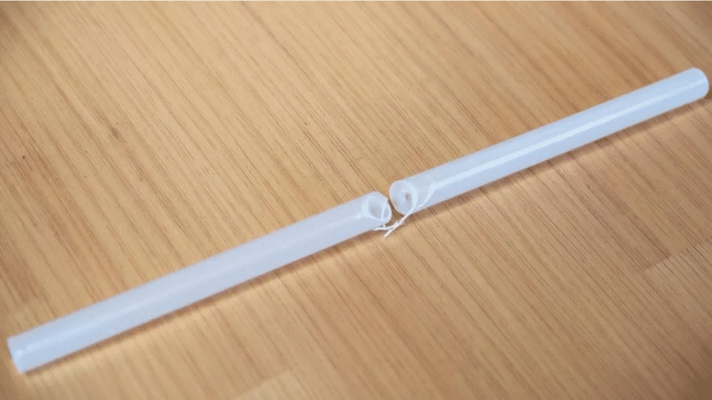 The image shows two straws being cut to a length of six to nine inches, with a small pin carefully pricking holes in the ends of each straw. This step is part of a DIY process to create bubble wands, perfect for kids to enjoy happy bubbling and making big bubbles.