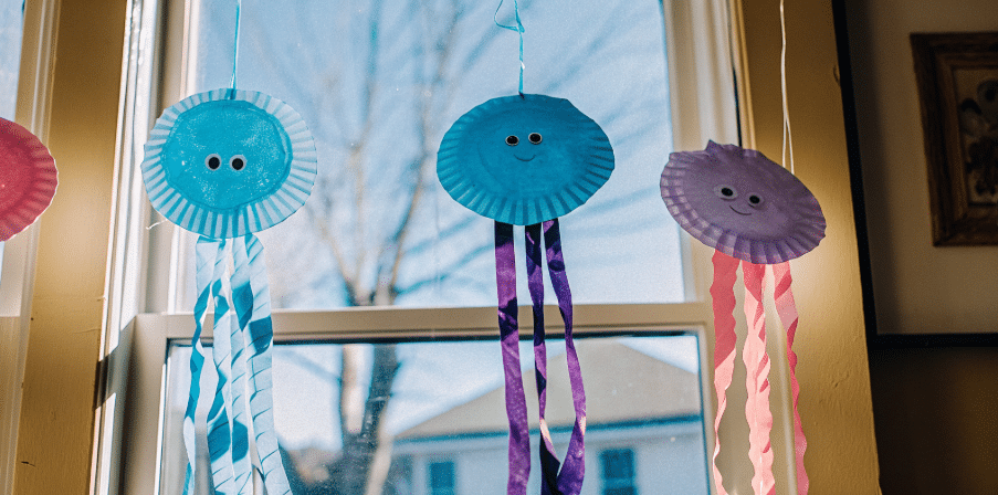 Jellyfish suncatchers made from colorful materials.