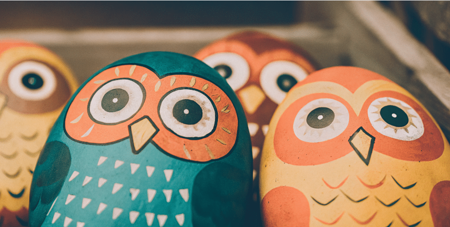 Painted Owl Stones The image features a collection of beautifully painted owl stones, showcasing various unique designs created by kids. These adorable owl crafts serve as charming garden decor and highlight the creativity and artistic expression of children through this fun and simple craft project.