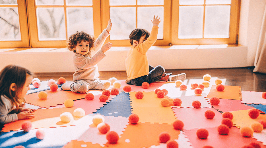 The image depicts preschoolers engaging in a fun math craft activity where they practice counting using colorful pom poms and construction paper. They are matching numbers to objects, reinforcing their counting skills while enjoying hands-on learning in a creative environment.