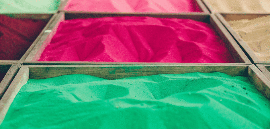 Different color sand in a wooden box.