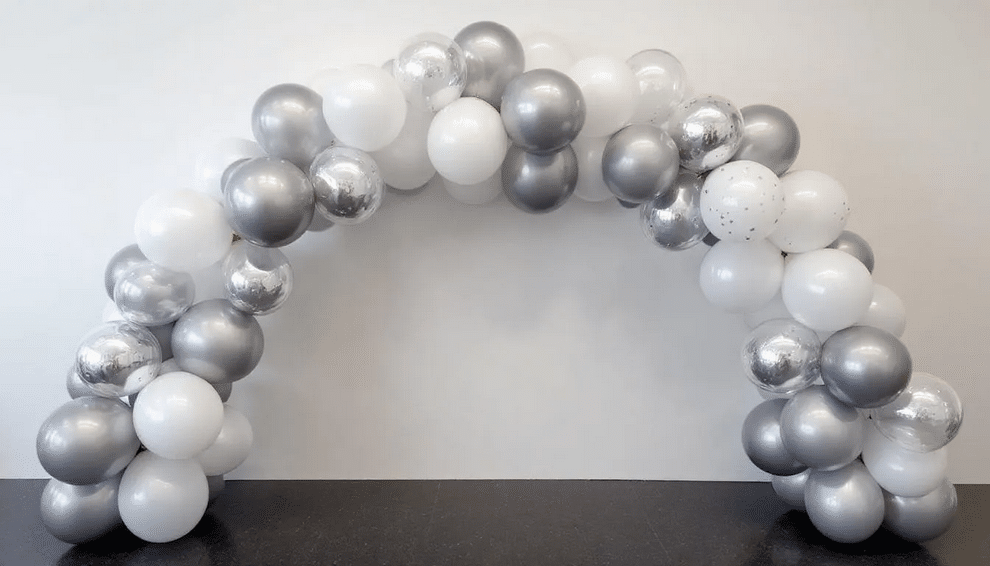 The image features a vibrant balloon arch made from a variety of balloons in metallic silver, light grey, and white, creating a festive atmosphere perfect for any party or special occasion. This daisy balloon arch is elegantly designed to enhance the celebration, showcasing the versatility and creativity possible with a balloon arch kit.