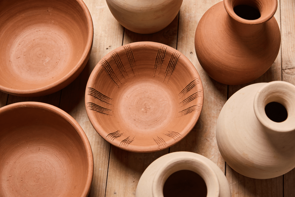 The image depicts a collection of earthenware pottery, showcasing its warm, earthy tones and textured surfaces. This type of clay, ideal for beginners, is perfect for hand building and wheel throwing, highlighting the versatility of clay and modeling materials.